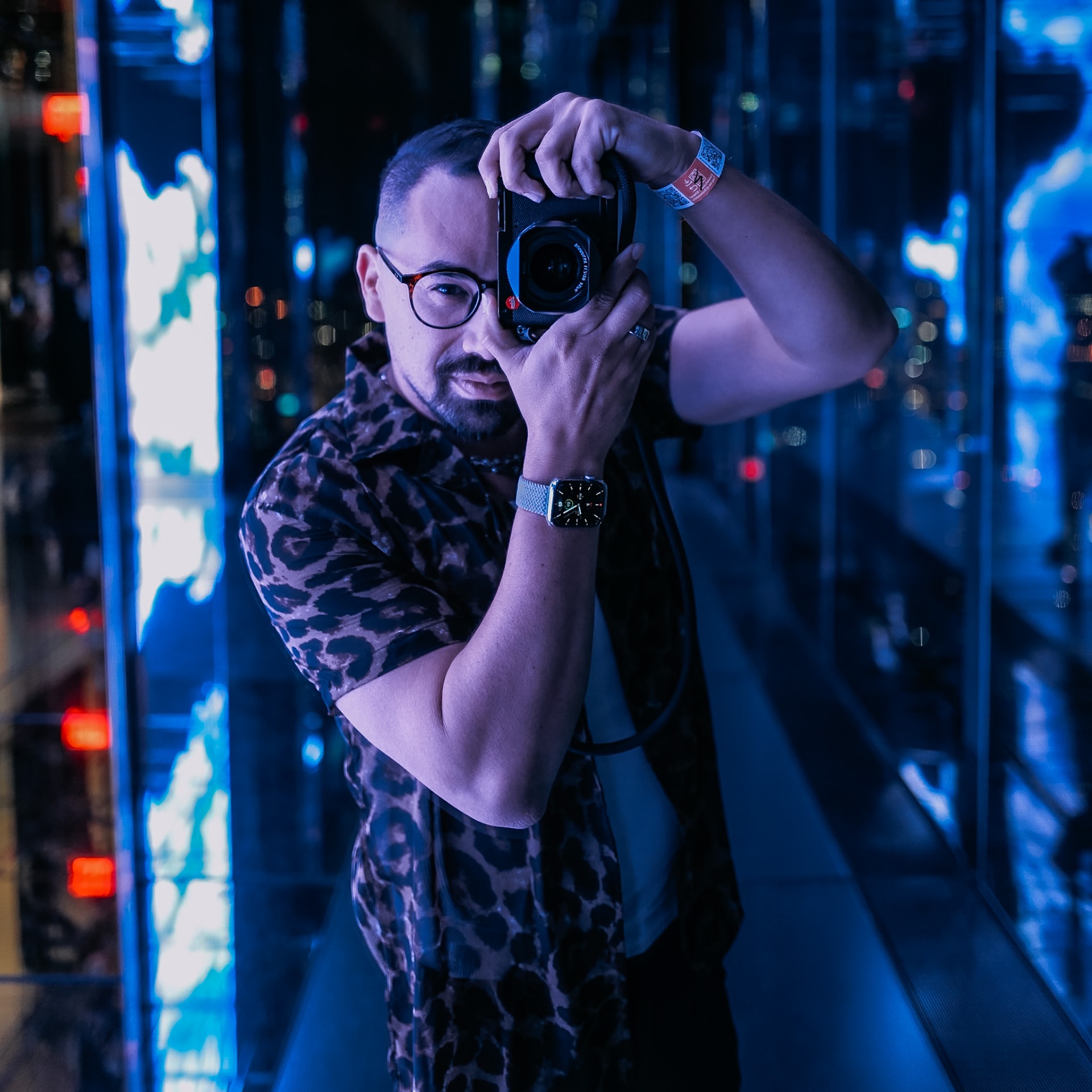 Ryan with camera, neon-lit cityscape reflection